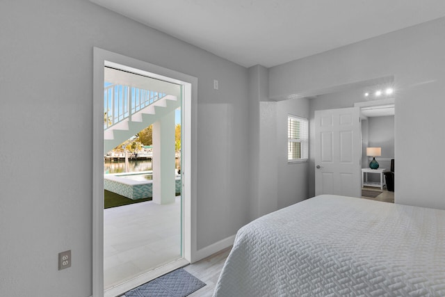 bedroom featuring wood finished floors, a water view, and baseboards