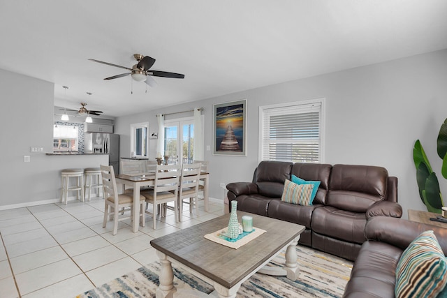 living room featuring baseboards, light tile patterned floors, and ceiling fan