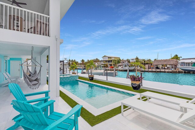 view of swimming pool with a water view, a pool with connected hot tub, and a dock