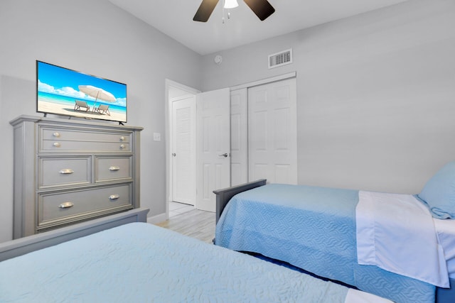 bedroom with light wood-type flooring, a ceiling fan, a closet, and baseboards