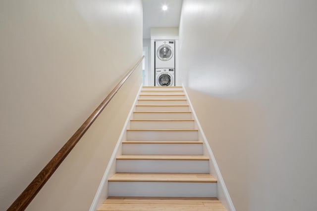 stairs with wood finished floors and stacked washer and clothes dryer