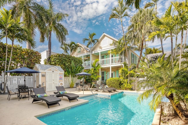 pool with a patio area, fence, and an outdoor structure