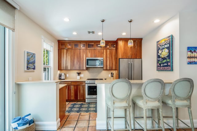 kitchen with pendant lighting, light countertops, visible vents, appliances with stainless steel finishes, and glass insert cabinets