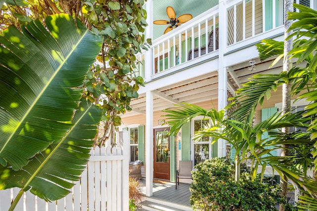 view of exterior entry with fence and a ceiling fan