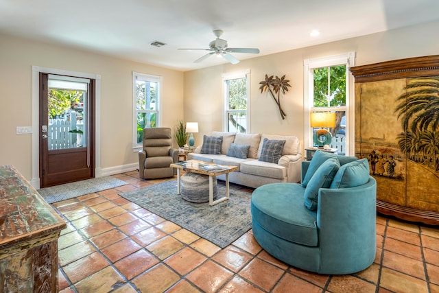 tiled living area with a ceiling fan, a wealth of natural light, visible vents, and baseboards