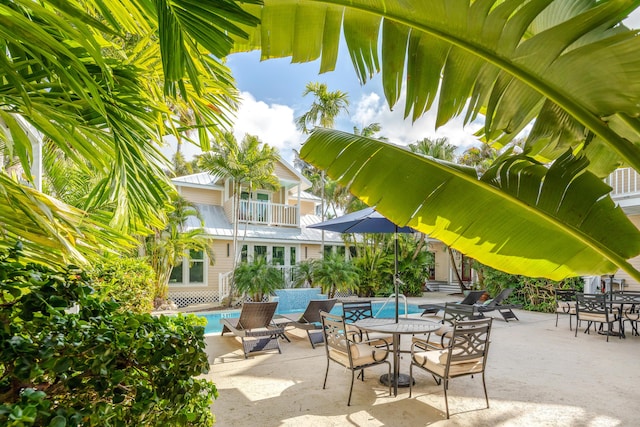 view of patio / terrace featuring a balcony, outdoor dining area, and an outdoor pool