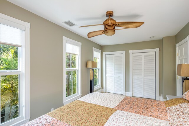 bedroom with multiple closets, visible vents, and ceiling fan