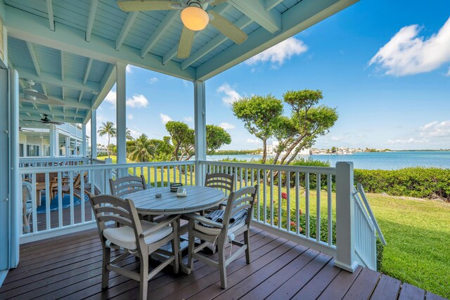 wooden deck featuring a water view, ceiling fan, and a lawn