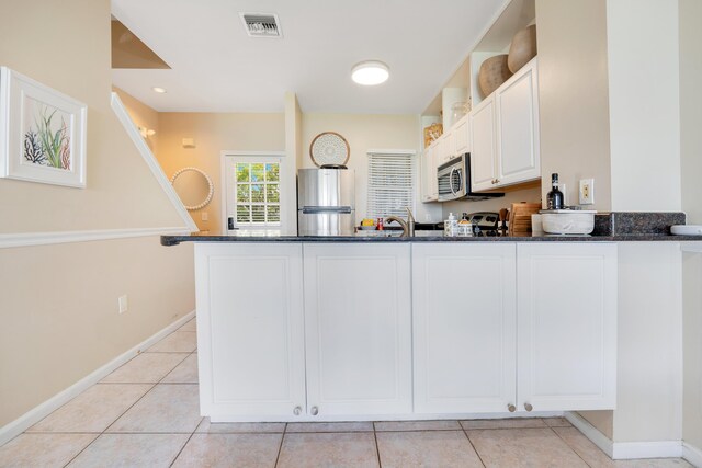 kitchen featuring dark stone countertops, stainless steel appliances, kitchen peninsula, and white cabinets