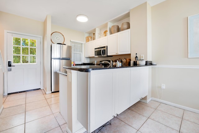 kitchen featuring white cabinetry, appliances with stainless steel finishes, light tile patterned flooring, and kitchen peninsula