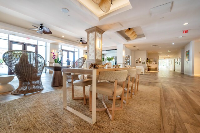 dining area with a tray ceiling, light hardwood / wood-style flooring, and ceiling fan