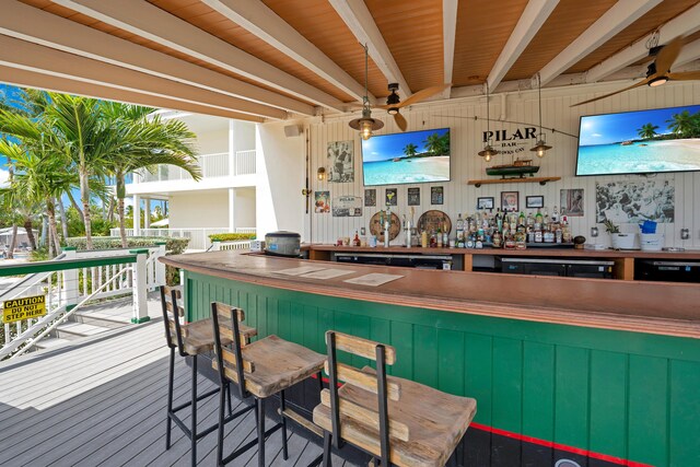 bar featuring beamed ceiling, hardwood / wood-style flooring, pendant lighting, and green cabinetry