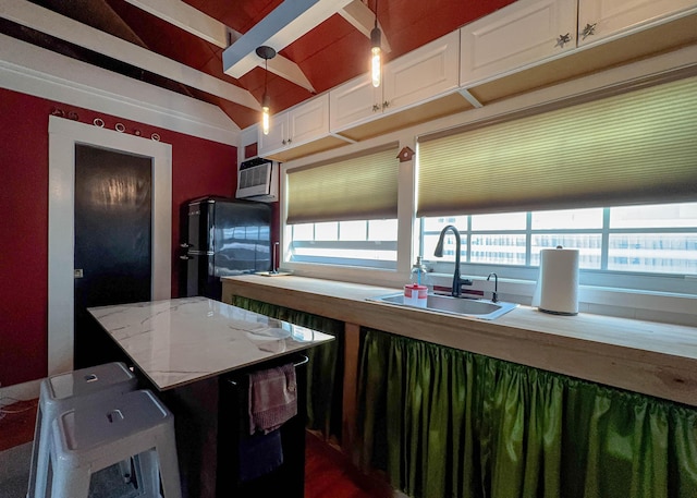 kitchen featuring sink, wooden counters, white cabinetry, hanging light fixtures, and black fridge