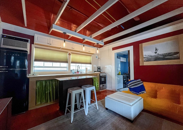 kitchen featuring decorative light fixtures, lofted ceiling with beams, sink, a breakfast bar area, and black fridge