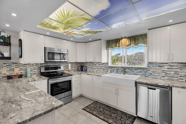 kitchen featuring light tile patterned flooring, tasteful backsplash, white cabinetry, sink, and stainless steel appliances