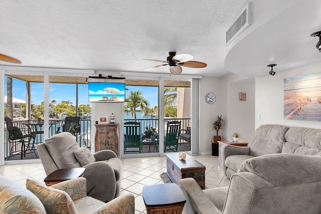 living room with ceiling fan, a wall of windows, a textured ceiling, and light tile patterned floors