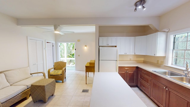 kitchen with freestanding refrigerator, light countertops, a sink, and light tile patterned floors