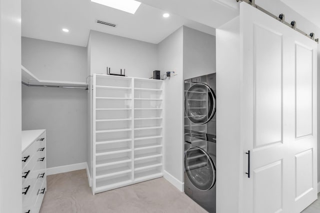 laundry area featuring stacked washing maching and dryer and a barn door