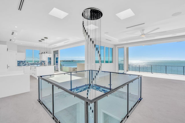 interior space with a water view, sink, a wealth of natural light, and a tray ceiling