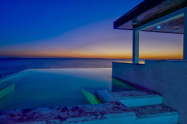 pool at dusk featuring a water view