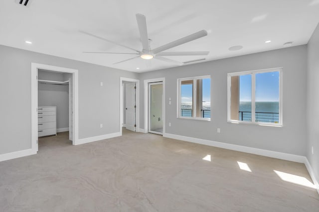 unfurnished bedroom with a spacious closet, ceiling fan, and a water view