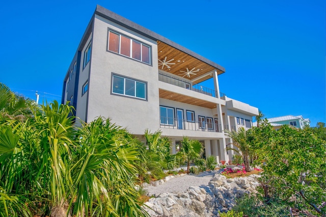 rear view of house with ceiling fan and a balcony