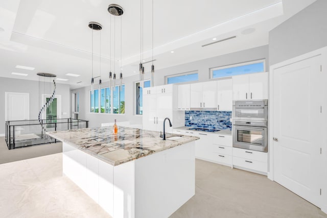 kitchen featuring white cabinetry, a center island with sink, and decorative light fixtures