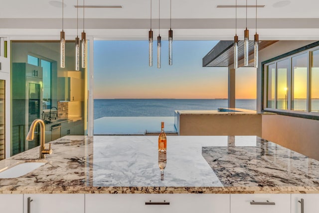 kitchen featuring hanging light fixtures, a water view, and white cabinets