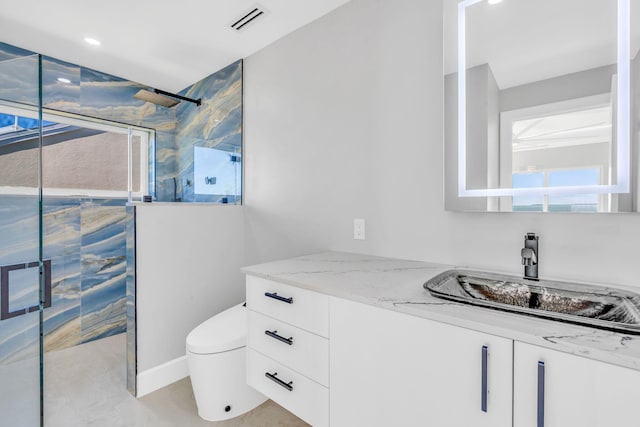 bathroom with vanity, a shower with door, and toilet