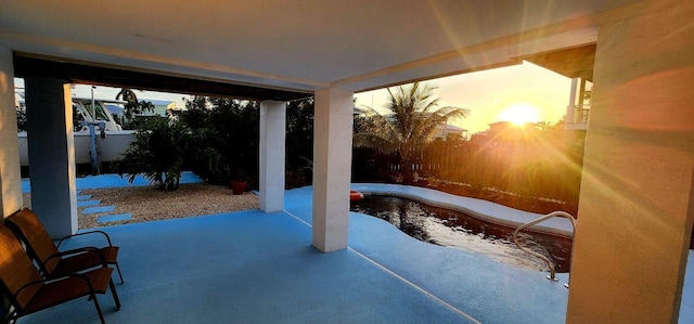 patio terrace at dusk with a fenced in pool