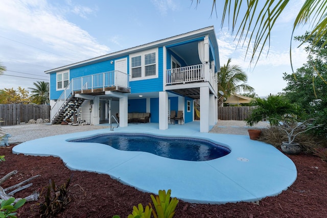 rear view of property featuring a fenced in pool, a balcony, and a patio area