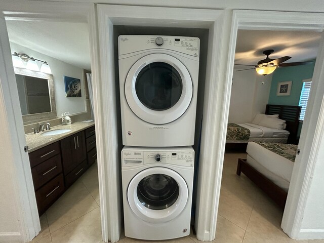 laundry area with stacked washer / drying machine, light tile patterned floors, sink, and ceiling fan