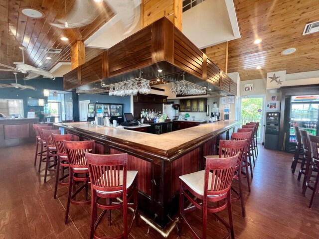 bar featuring dark wood-type flooring, high vaulted ceiling, and wooden ceiling