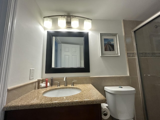 bathroom featuring toilet, tile walls, vanity, and a shower with shower door