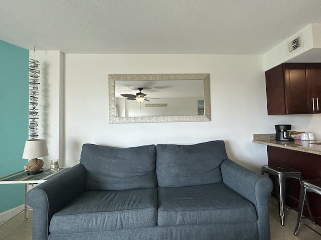 living room with a textured ceiling and ceiling fan