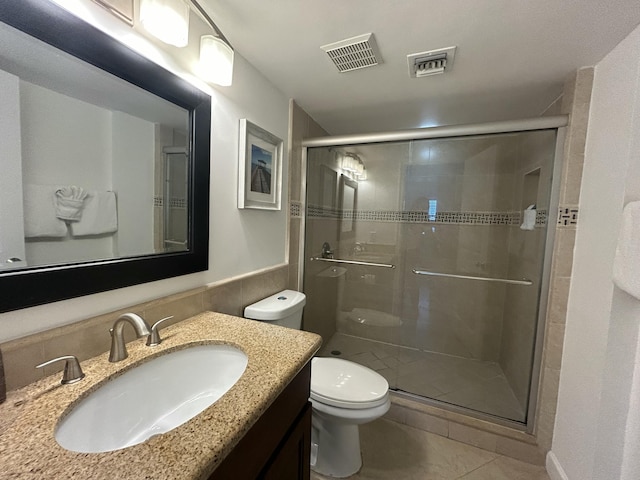 bathroom featuring tile patterned flooring, vanity, a shower with shower door, and toilet