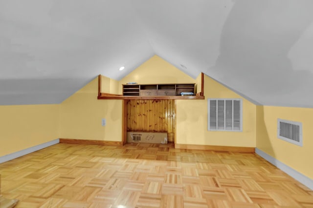 additional living space featuring baseboards, visible vents, and vaulted ceiling