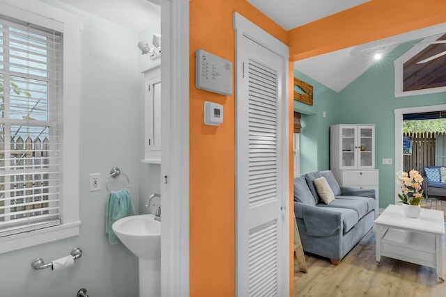 bathroom featuring a sink, ensuite bath, vaulted ceiling, and wood finished floors