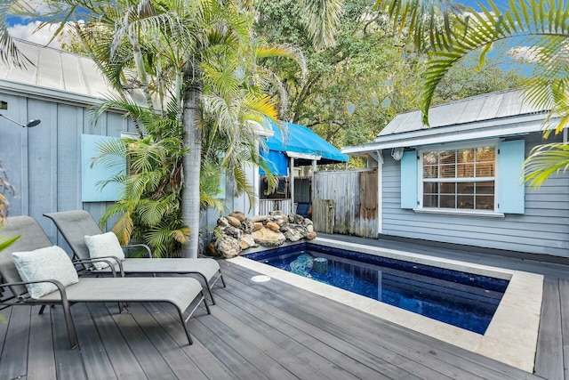 view of swimming pool with a jacuzzi, fence, and a deck