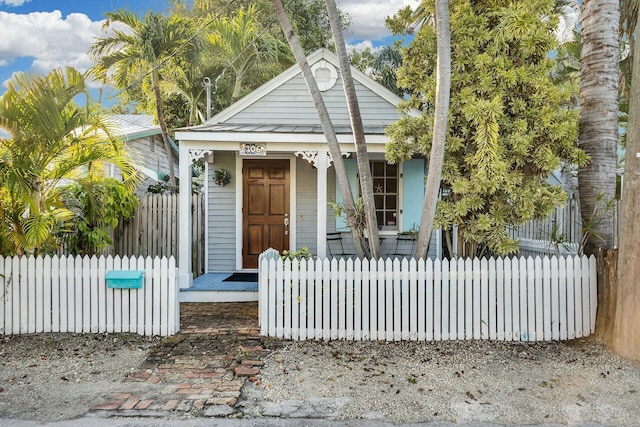 view of front facade with a fenced front yard, covered porch, and metal roof