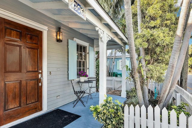 entrance to property with covered porch and fence