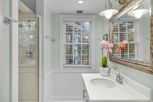 bathroom featuring a wainscoted wall, a shower with shower door, vanity, and visible vents