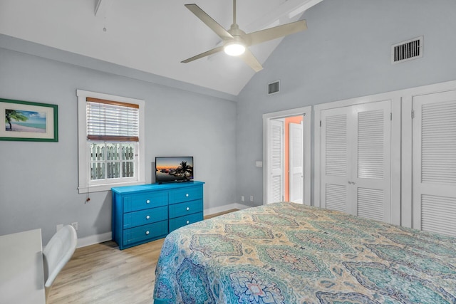 bedroom with lofted ceiling, light wood-type flooring, visible vents, and baseboards