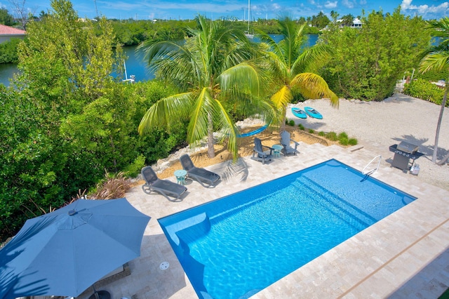 view of swimming pool featuring a patio area and a water view