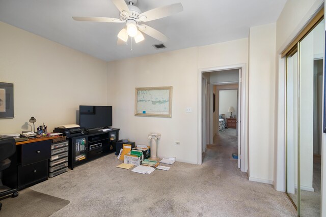 office area featuring a ceiling fan, visible vents, and light carpet