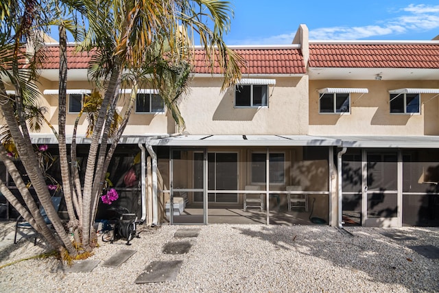 back of house with a sunroom, a tiled roof, and stucco siding