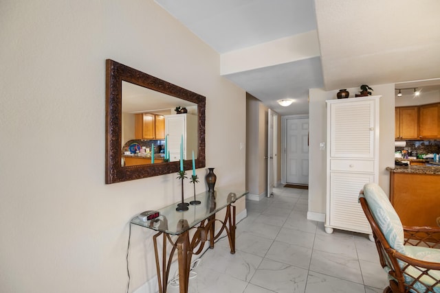 hallway with marble finish floor and baseboards