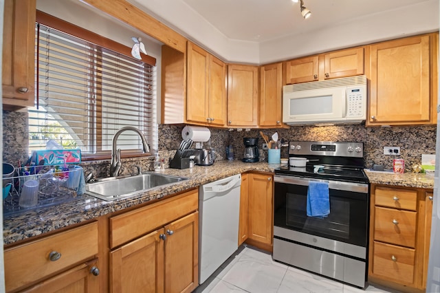 kitchen with white appliances, stone counters, decorative backsplash, and a sink