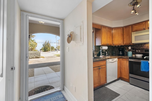 kitchen featuring white appliances, brown cabinets, baseboards, and decorative backsplash