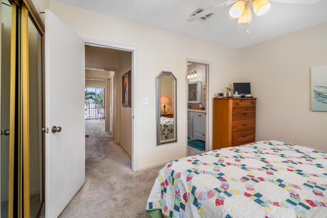 bedroom featuring ceiling fan, light colored carpet, visible vents, baseboards, and ensuite bath